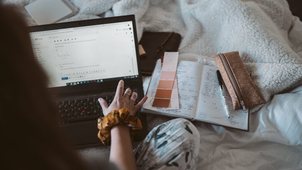 writing an email on a laptop sitting on the bed